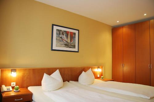 a hotel room with a bed with white pillows at Hotel Verdi in Rostock