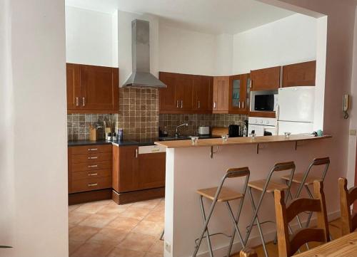 uma cozinha com armários de madeira e uma ilha com bancos de bar em Appartement de charme dans maison de maître bruxelloise em Bruxelas