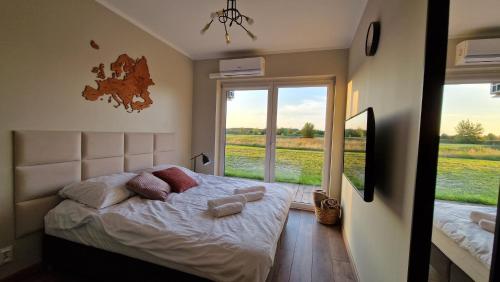 a bedroom with a bed and a large window at Apartament Golf & Nature - Na Polu Golfowym in Sobienie Biskupie