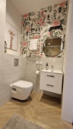 W łazience znajduje się toaleta, umywalka i lustro. w obiekcie Apartament Golf & Nature - Na Polu Golfowym w mieście Sobienie Biskupie