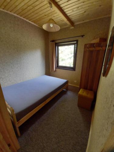 um pequeno quarto com uma cama e uma janela em Rūnēnu zāļu namiņš em Vidzeme
