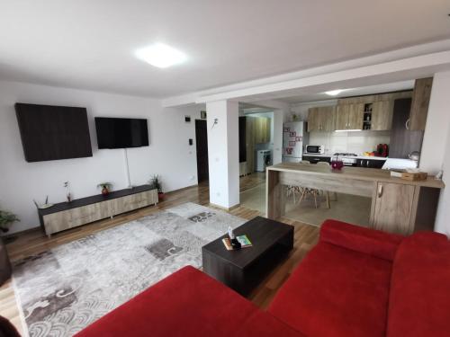 a living room with a red couch and a kitchen at Apartament Ovidiu in Giroc