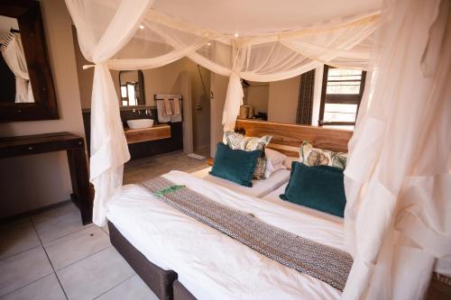 a bedroom with a canopy bed with blue pillows at Toshari Lodge in Okaukuejo