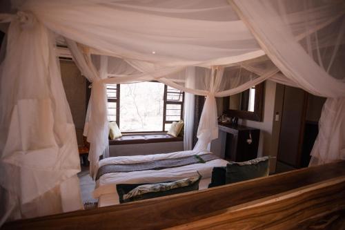 a bedroom with a canopy bed and a window at Toshari Lodge in Okaukuejo