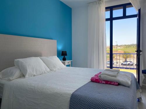 1 dormitorio con 1 cama con pared azul y ventana en Bahia Meloneras Vista Golf en Meloneras