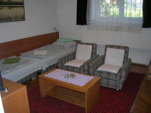 a room with two beds and two chairs and a table at Táncsics magánszállás Pécs in Pécs