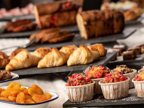 a table topped with trays of pastries and bread at Hôtel Ski Lodge - Chambres & Appartements - Village Montana in Val dʼIsère