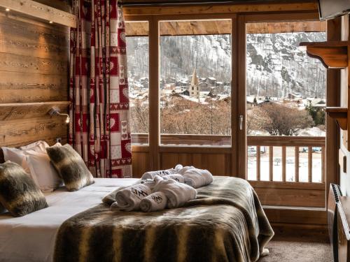 a bed in a room with a large window at Hôtel Ski Lodge - Village Montana in Val dʼIsère
