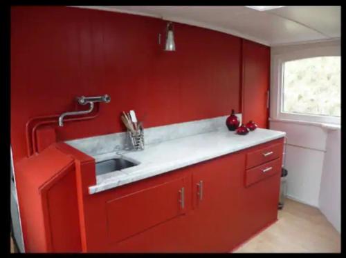 een rode keuken met een wastafel en een raam bij Houseboat Orfeo in Gent