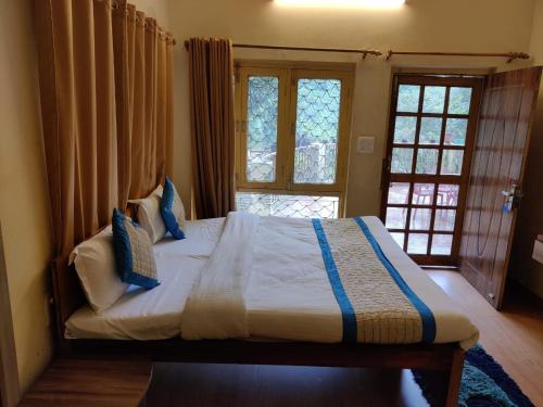 1 Schlafzimmer mit einem großen Bett und 2 Fenstern in der Unterkunft The Woods in Nainital