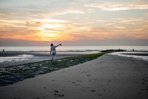 a woman standing on the beach at sunset at les Cabanes d'Ostende in Ostend