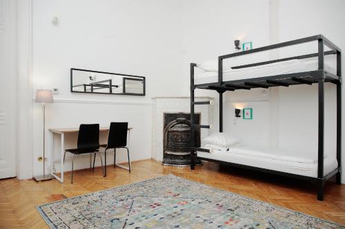 a bedroom with two bunk beds and a table and chairs at Maverick Hostel & Ensuites in Budapest
