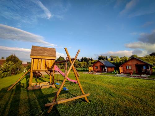 a wooden playground in a field with a house at Zielona Dolina Hoczew in Hoczew