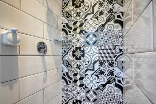 a shower with a black and white tile wall at Hampton Collection - Charming 1 or 2 Bedroom Apartment with Pool in Durban
