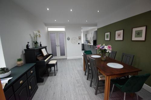 a dining room and living room with a table and a piano at Ideal Lodgings in Accrington in Accrington
