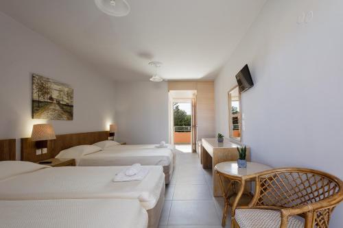 a hotel room with two beds and a tv at Rethymno Village in Platanes