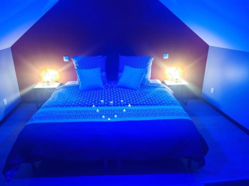 een blauwe slaapkamer met een groot bed met 2 verlichting bij Côté spa 