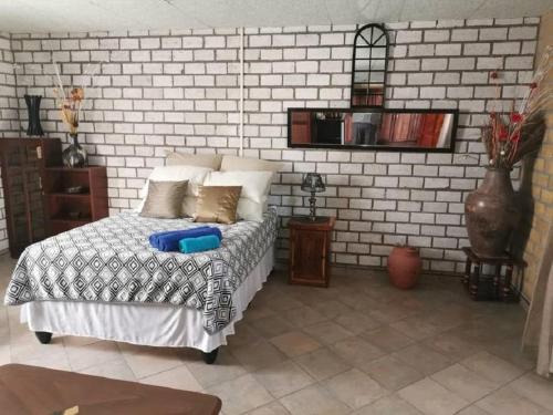 1 dormitorio con 1 cama y pared de ladrillo blanco en Palmeiras Lodge Oshikango en Oshikango