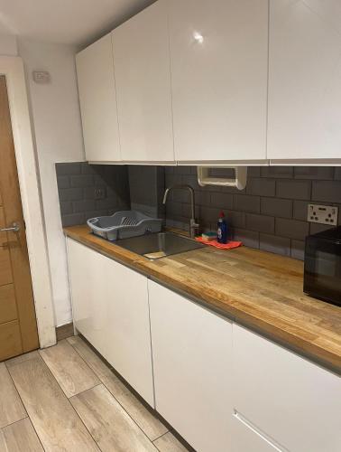 uma cozinha com armários brancos e um lavatório em Tee's apartments em Plumstead