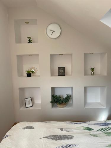 a bedroom with a white wall with shelves and a clock at Domek w górach in Barcice