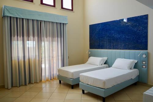 Toscana Sport Resort في تيرّينيا: غرفة بسريرين ولوحة على الحائط