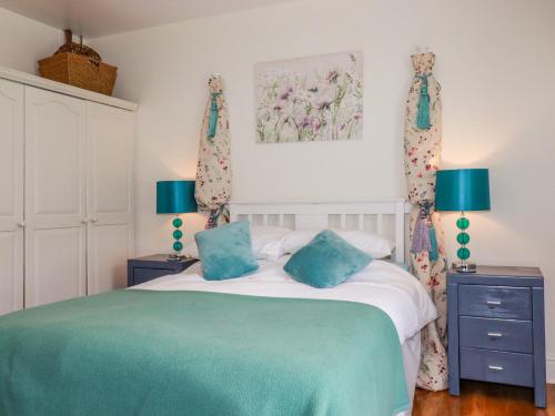 a bedroom with a bed with two blue pillows at Vis Valley View in Pentewan