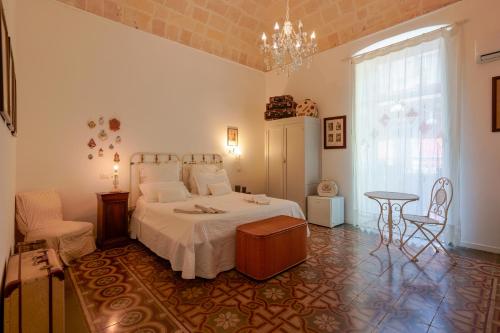 una camera con letto, tavolo e lampadario a braccio di B&B Il Melograno Taranto a Taranto