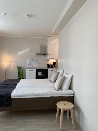 a white bedroom with a bed and a table at Hotel Aakenus Apartment Korkalo in Rovaniemi