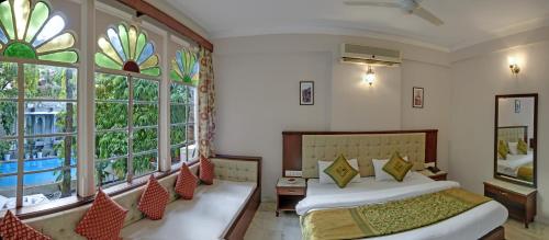 a bedroom with two beds and a large window at Hotel Raj Palace by Howard in Udaipur