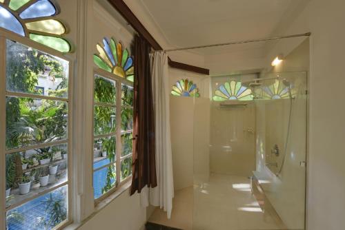 a bathroom with a walk in shower next to a window at Hotel Raj Palace by Howard in Udaipur