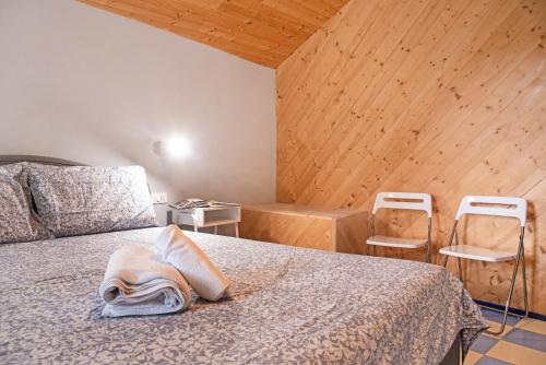 a bedroom with a bed and two white chairs at Cadepaia Lago Maggiore in Laveno-Mombello