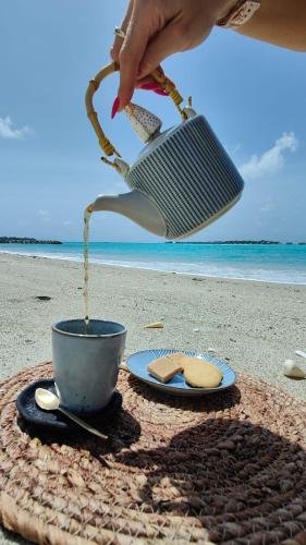 a person pouring sand into a cup on the beach at Chambao Maldives in Guraidhoo
