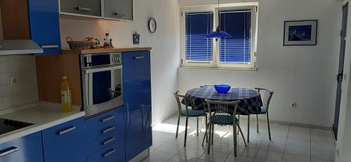 une cuisine avec une table, des chaises et un meuble bleu dans l'établissement Pepermint, à Baška Voda