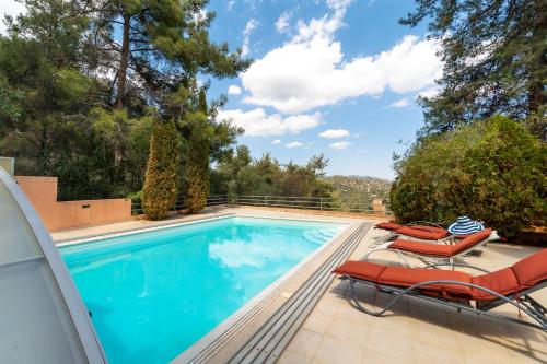 une piscine avec deux chaises longues et une piscine dans l'établissement Villa Hillcrest Panorama by Ezoria Villas, à Moniatis