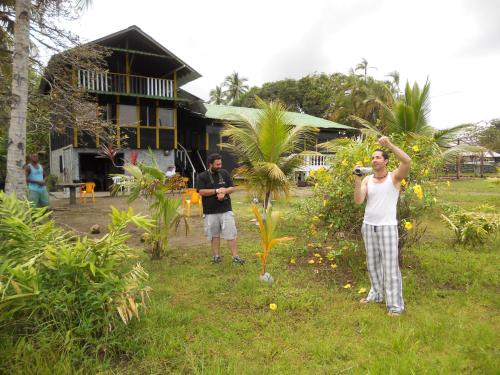 two men standing in the grass in front of a house at Hotel Nuquimar in Nuquí