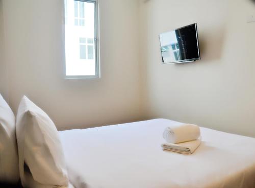 a bedroom with a white bed with a tv on the wall at Gem Hotel Nusa Sentral Nusajaya in Johor Bahru