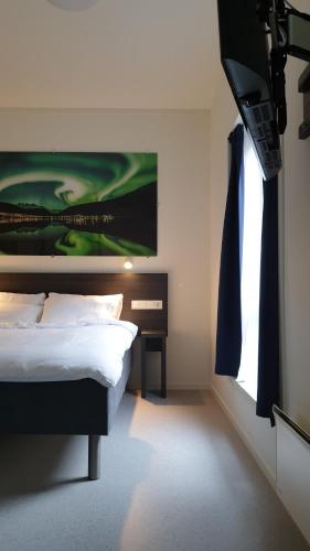 a bedroom with a bed and a tv on the wall at Aiden by Best Western Harstad Narvik Airport in Harstad