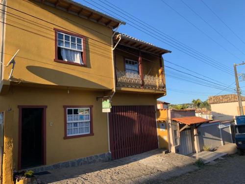 une maison jaune avec une planche de surf sur un balcon dans l'établissement Hostel Lumiar da Serra, à Tiradentes