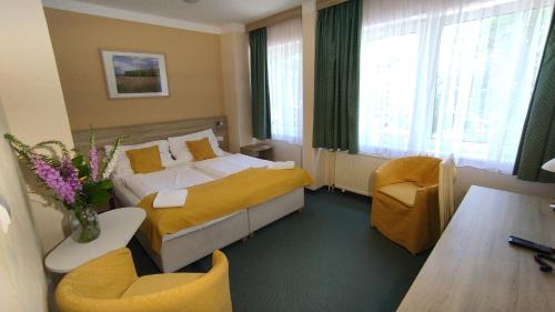 Habitación de hotel con cama, mesa y sillas en Parkhotel Sokolov, en Sokolov
