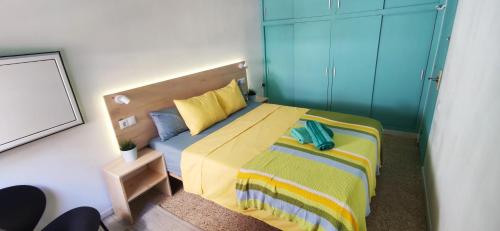 a bedroom with a large bed with yellow and blue sheets at Casa Petits in Manresa