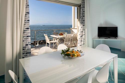 a white dining room with a view of the ocean at Ischia Blu Resort in Ischia