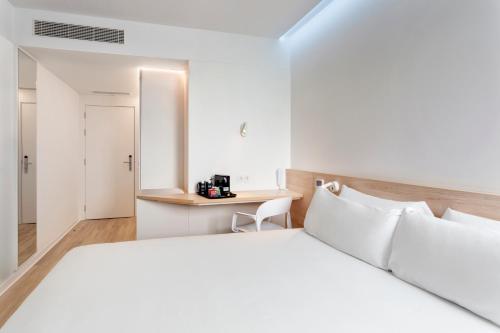 1 dormitorio con cama blanca y escritorio en B&B HOTEL Famalicão en Vila Nova de Famalicão