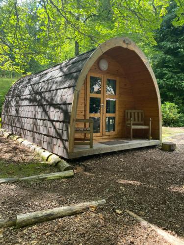 a small wooden dome house with a bench in it at Fairburn Activity Centre in Contin