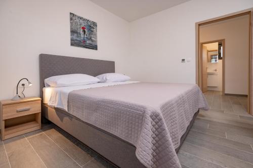 um quarto com uma cama com uma colcha branca e uma mesa em Kuća za odmor Sara em Privlaka