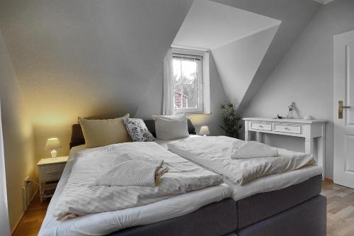 a bedroom with a large white bed with a window at Am Deich 43 in Zingst