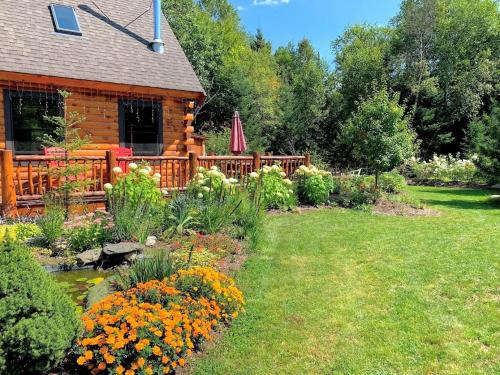 a garden in front of a log cabin at BC Log cabin with private beach river fire pit AC wifi onsite trails ski slope views in Carroll