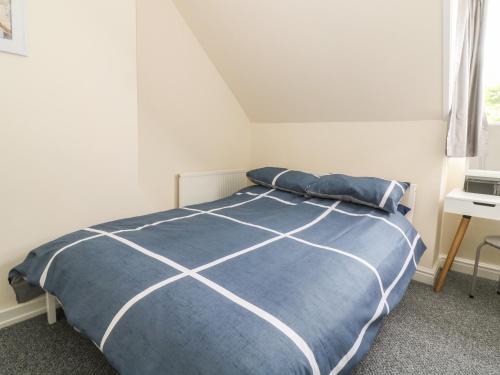 a bedroom with a bed with a blue comforter at The Pebbles in Hornsea