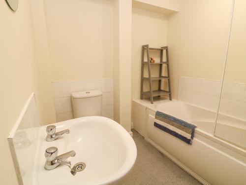 a white bathroom with a sink and a bath tub at The Pebbles in Hornsea