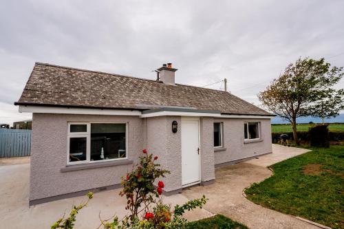 a white house with a large window at Holmestead Cottage in Tyrella