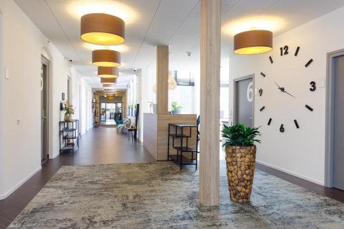 a hallway with a clock on the wall and a plant at B&B Landgoed De Grote Beek in Eindhoven